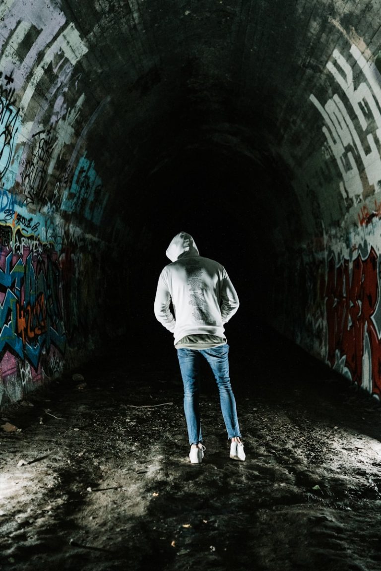 man in gray hoodie walking on tunnel
