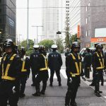 group of men in blue and yellow jacket standing on sidewalk during daytime