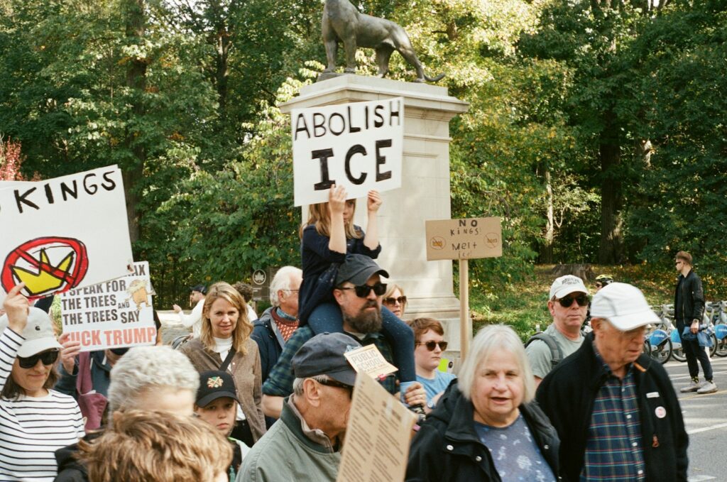 Protesters hold signs at a rally near a statue.